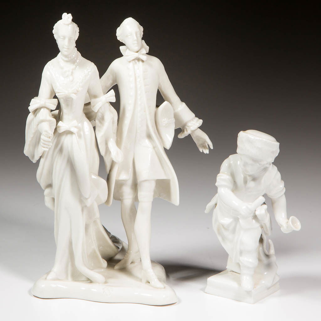 GERMAN NYMPHENBURGER AND KPM BLANC DE CHINE FIGURES,: GERMAN NYMPHENBURGER AND KPM BLANC DE CHINE FIGURES, LOT OF TWO, comprising a standing couple on base, woman holding flower forward and man holding tricorn hat, and boy holding cup or bell and small p