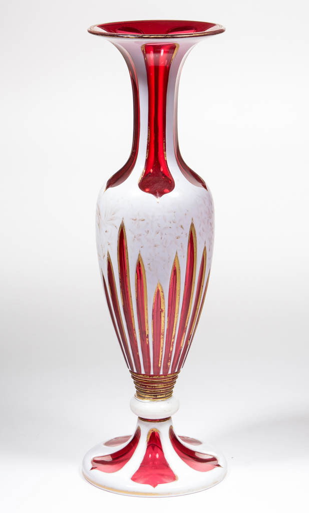 EUROPEAN CUT OVERLAY VASE: EUROPEAN CUT OVERLAY VASE, opaque white to cranberry with gilt decoration, tall urn-form with a flared rim, body with long ray/prism cuts, with elongated ovoid cuts to the neck, knop connector, circul