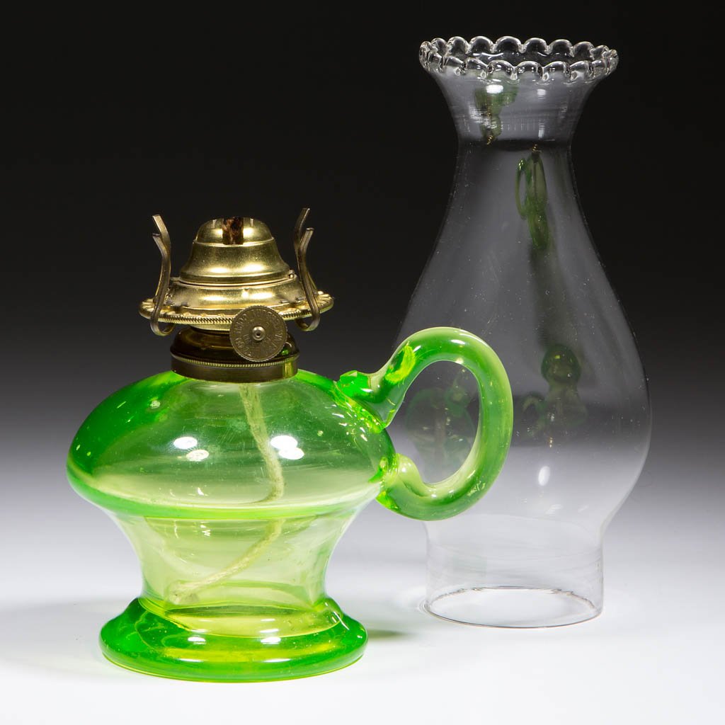 BLOWN-MOLDED KEROSENE FOOTED FINGER LAMP: BLOWN-MOLDED KEROSENE FOOTED FINGER LAMP, bright Vaseline (black lighted), waisted form with reverse applied handle with a factory polished tip to the upper terminal of handle, period No. 1 collar. Fi