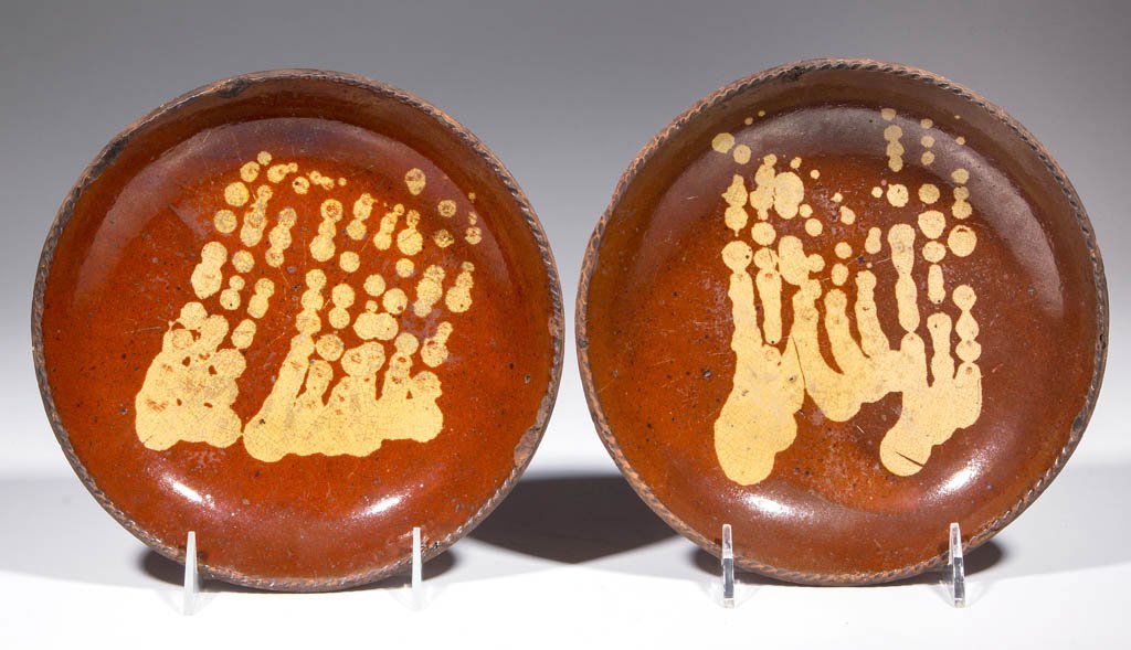 AMERICAN SLIP-DECORATED EARTHENWARE / REDWARE PLATES,: AMERICAN SLIP-DECORATED EARTHENWARE / REDWARE PLATES, LOT OF TWO, lead-glazed, with lightly coggled rims. Near matching yellow-slipped decorations to centers. First half 19th century. 1 1/2" H, 8 5/8"