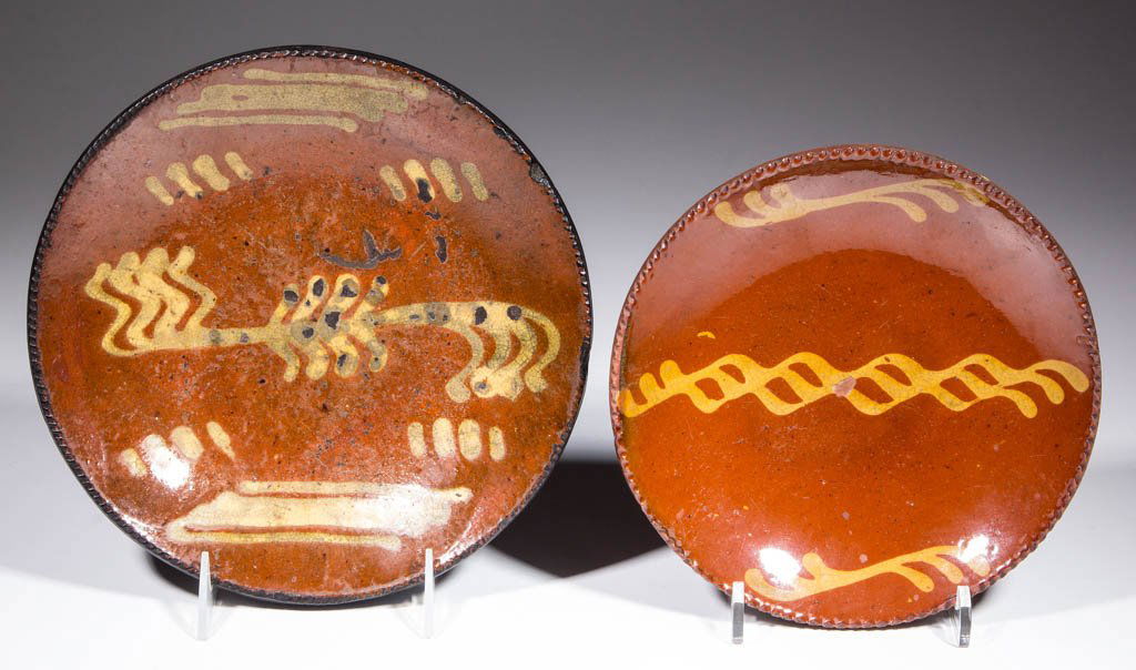 AMERICAN SLIP-DECORATED EARTHENWARE / REDWARE PLATES,: AMERICAN SLIP-DECORATED EARTHENWARE / REDWARE PLATES, LOT OF TWO, lead-glazed, with lightly coggled rims. Yellow-slipped stylized clef decorations to centers. First half 19th century. 8" and 9 1/4" D.