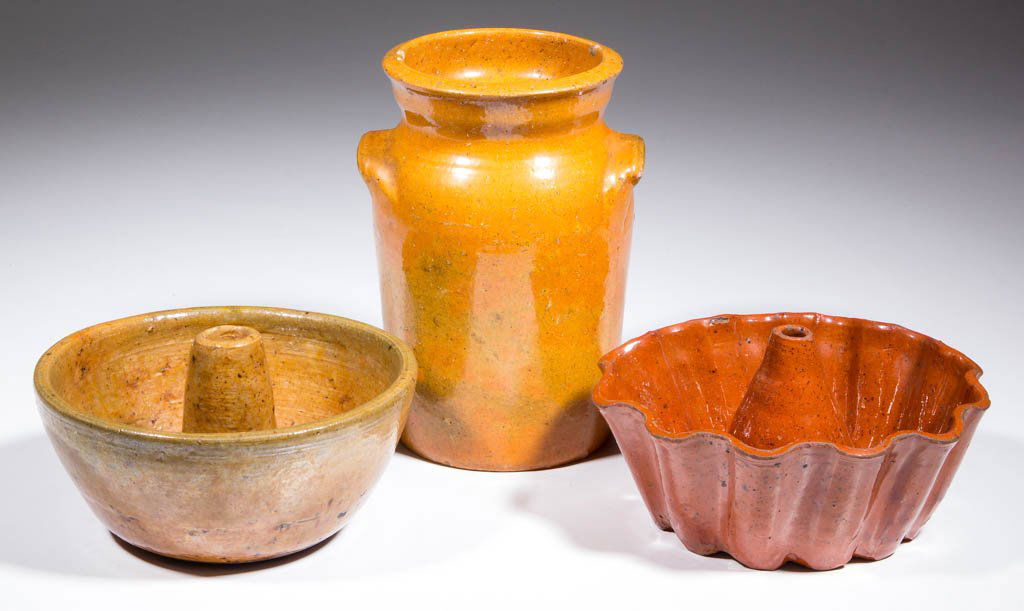 AMERICAN EARTHENWARE / REDWARE DOMESTIC ARTICLES, LOT: AMERICAN EARTHENWARE / REDWARE DOMESTIC ARTICLES, LOT OF THREE, lead-glazed, comprising two food molds and a child's butter churn with handles, probably North Carolina. Second half 19th/early 20th cen