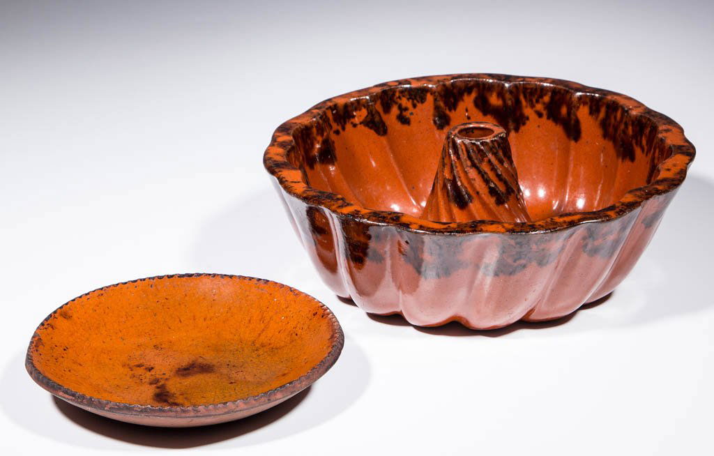 AMERICAN DECORATED EARTHENWARE / REDWARE DOMESTIC: AMERICAN DECORATED EARTHENWARE / REDWARE DOMESTIC ARTICLES, LOT OF TWO, lead- and manganese-glazed, comprising a diminutive plate with coggled rim and a turk's head mold stamped "10" to underside. Eac