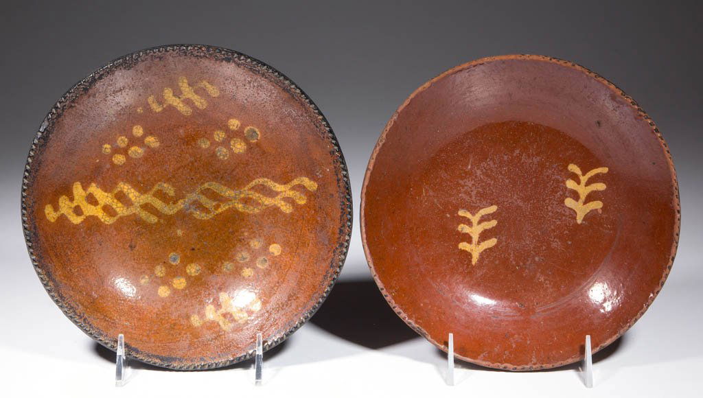 AMERICAN SLIP-DECORATED EARTHENWARE / REDWARE PLATES,: AMERICAN SLIP-DECORATED EARTHENWARE / REDWARE PLATES, LOT OF TWO, lead-glazed, with coggled rims. Yellow-slipped sprig, wavy lines, and dot decorations to centers. First half 19th century. 1 1/2" H, 8