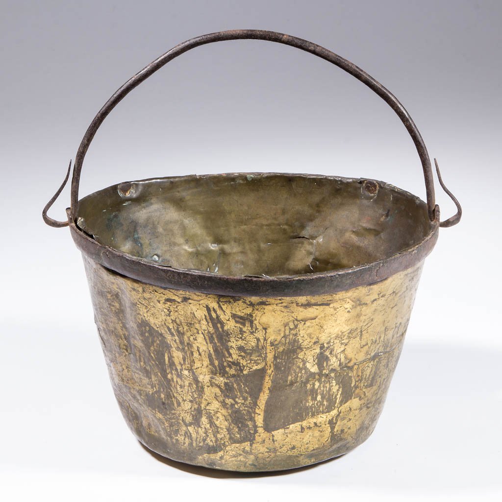 COLONIAL BRASS AND IRON TRADE KETTLE: COLONIAL BRASS AND IRON TRADE KETTLE, circular, with iron bail handle and applied rim, flat base. Collection information to painted white rectangle at interior. French manufacture. Mid 18th century. 8