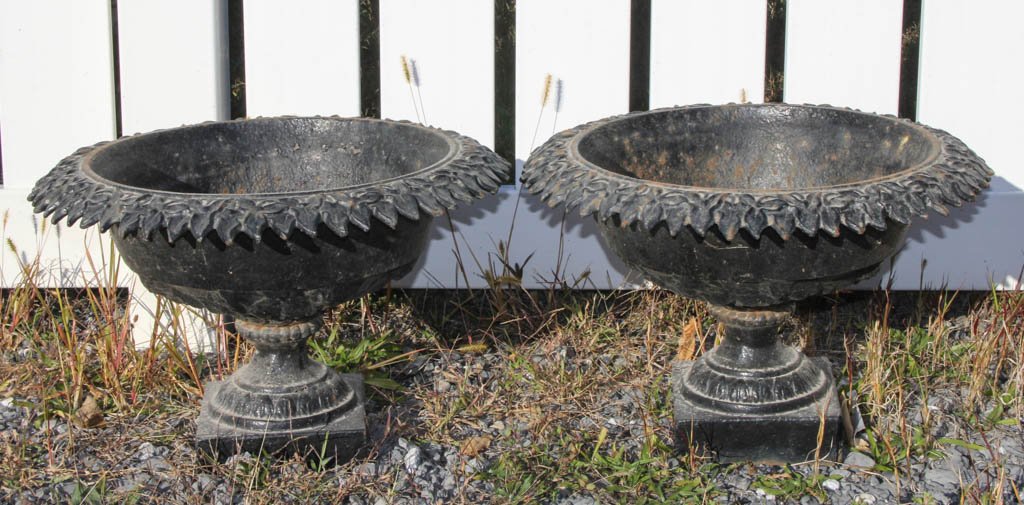 CLASSICAL STYLE CAST-IRON GARDEN URNS, PAIR: CLASSICAL STYLE CAST-IRON GARDEN URNS, PAIR, black-painted surface, each of squat circular form, with molded ivy pattern to rim shoulder, baluster-form standard with fluting above and below the medial