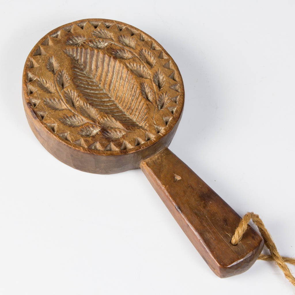 AMERICAN CARVED TREEN LOLLIPOP-STYLE BUTTER PRINT: AMERICAN CARVED TREEN LOLLIPOP-STYLE BUTTER PRINT, walnut, primary side hand-carved with a central leaf framed by sprays of small leaves, all within a sawtooth border, reverse with a lightly-carved he