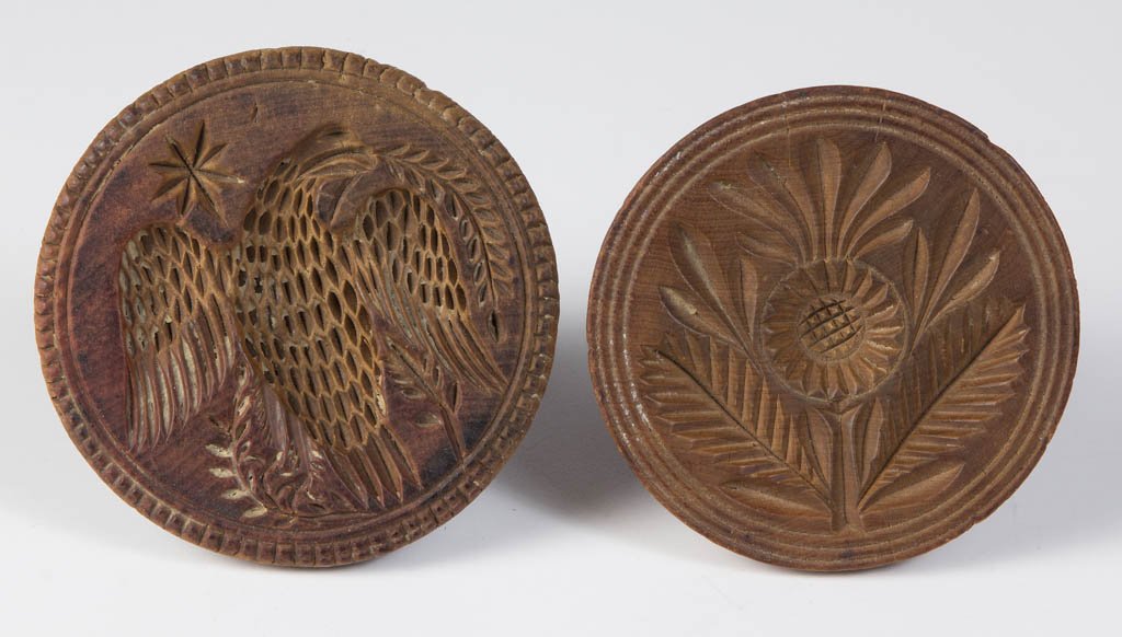 AMERICAN CARVED TREEN BUTTER PRINTS, LOT OF TWO: AMERICAN CARVED TREEN BUTTER PRINTS, LOT OF TWO, each of circular form with integral handle, one featuring a spread-wing eagle with star, other with a daisy-like flower and leaves. Old dark surfaces. 