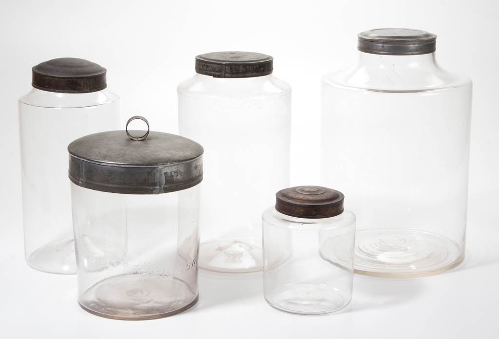 ASSORTED APOTHECARY / STORE JARS: ASSORTED APOTHECARY / STORE JARS, colorless glass, three free-blown and two blown-molded, one marked "P. B. & Co. / Philada.", each with tin cover. Second half 19th century. 6 1/8" to 13 1/4" H. Jars 