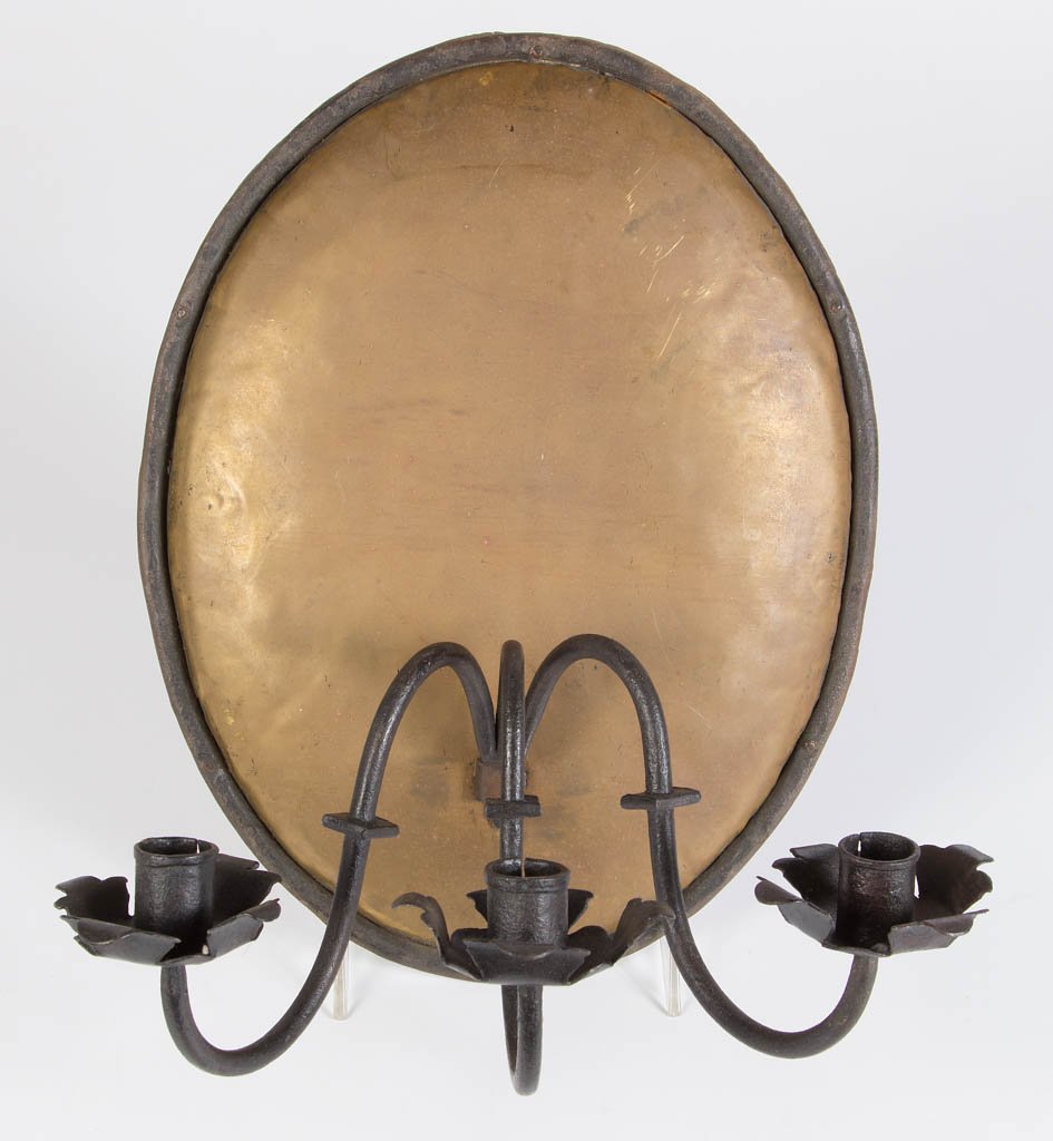 WROUGHT-IRON AND BRASS CANDLE SCONCE: WROUGHT-IRON AND BRASS CANDLE SCONCE, oval shield-like wall plate supporting three single-nozzle arms. Late 19th/early 20th century. 14" x 11" plate, 9" D. Very good condition. Provenance: Property of
