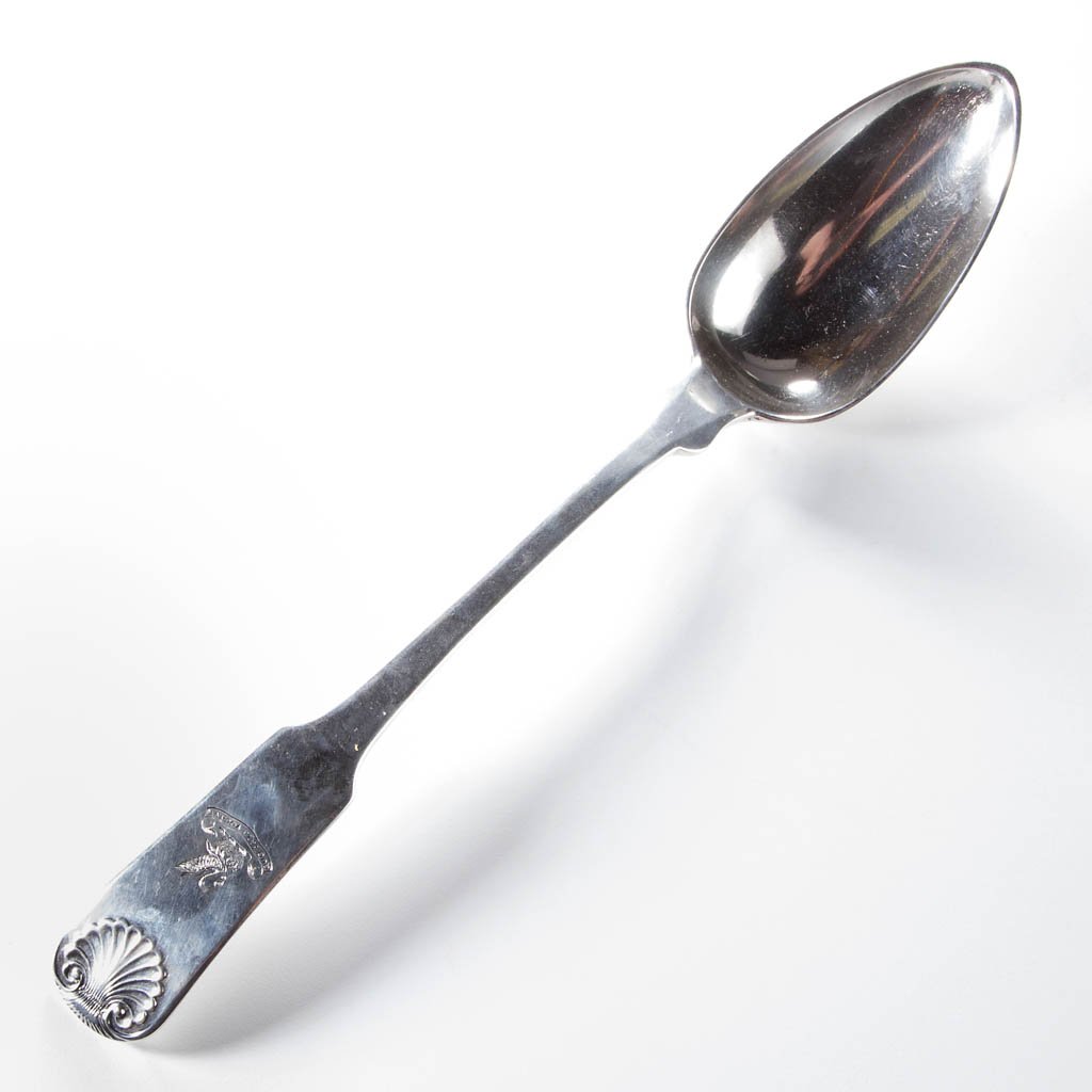 NEW YORK COIN SILVER SERVING SPOON: NEW YORK COIN SILVER SERVING SPOON, backward-tipped fiddle back with embossed shell decoration to handle, with crest-type decoration below the shell, depicting a vulning pelican with chicks and motto 