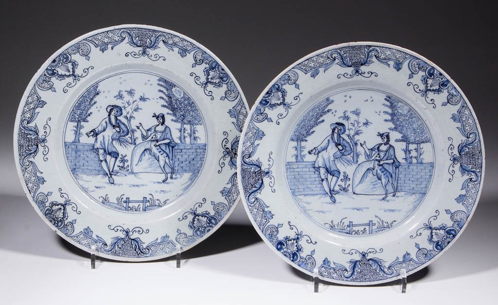 DUTCH DELFT TIN-GLAZED EARTHENWARE PAIR OF PLATES: DUTCH DELFT TIN-GLAZED EARTHENWARE PAIR OF PLATES, having courting figures and a dog in a landscape with intricate floral and geometric design on rim. Unmarked. 17th/early 18th century. 10 1/4" D.Exce