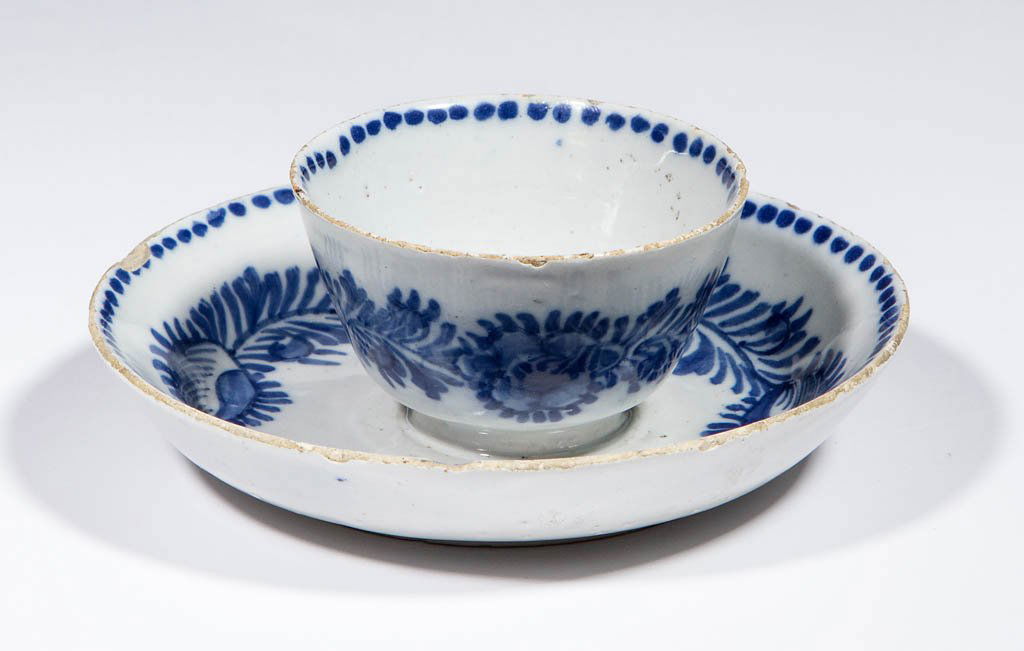 DUTCH DELFT TIN-GLAZED EARTHENWARE SWEETMEAT / PICKLE: DUTCH DELFT TIN-GLAZED EARTHENWARE SWEETMEAT / PICKLE DISH, in the shape of a cup and saucer fused together, having a detailed floral and vine design in blue on interior of base and side of cup/bowl,