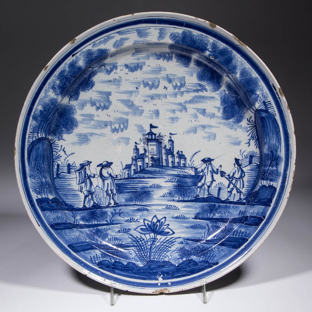 DUTCH DELFT TIN-GLAZED EARTHENWARE CHARGER: DUTCH DELFT TIN-GLAZED EARTHENWARE CHARGER, manorial landscape scene with figures in center and sponge-painted foliage around cavetto, blue linear designs on underside of rim and cavetto. Unmarked. La