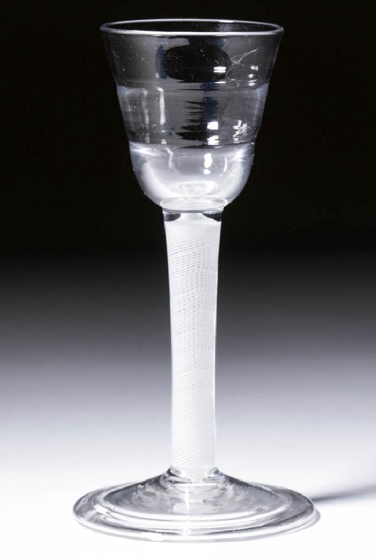 ENGLISH PATTERN-MOLDED OPAQUE-TWIST WINE GLASS: ENGLISH PATTERN-MOLDED OPAQUE-TWIST WINE GLASS, colorless lead glass, stepped round funnel "Lynn" bowl raised on a stem containing a multi-spiral twist, conical folded foot with rough pontil mark. 18t