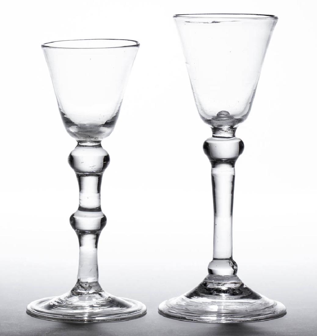 ENGLISH FREE-BLOWN BALUSTROID WINE GLASSES, LOT OF TWO: ENGLISH FREE-BLOWN BALUSTROID WINE GLASSES, LOT OF TWO, colorless lead glass, each with pointed round funnel bowl, one stem with shoulder and basal knops, other with shoulder and center knop, each on 