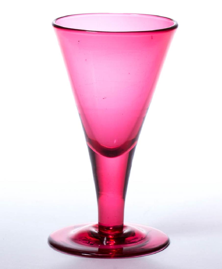 ENGLISH FREE-BLOWN WINE GLASS: ENGLISH FREE-BLOWN WINE GLASS, cranberry/ruby, funnel bowl raised on a drawn solid stem and slightly domed foot with rough pontil mark. Early 19th century. 4 3/8" H, 2 1/2" D foot. Undamaged. Provenan