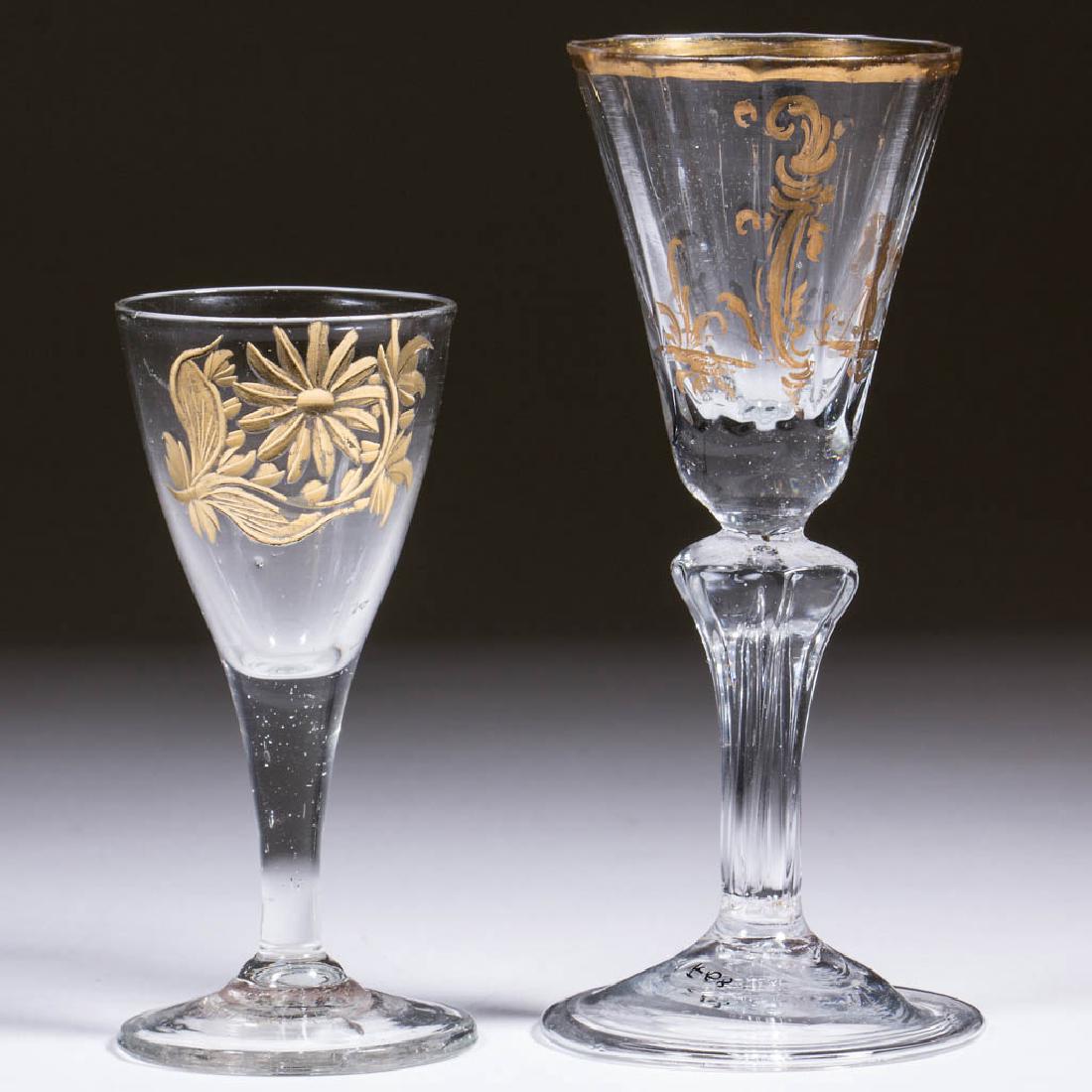 CONTINENTAL BLOWN AND GILDED WINE GLASSES, LOT OF TWO: CONTINENTAL BLOWN AND GILDED WINE GLASSES, LOT OF TWO, colorless non-lead glass, comprising a free-blown example with ogee bowl, engraved and gilded flower decoration, and drawn stem, and a pattern-mo