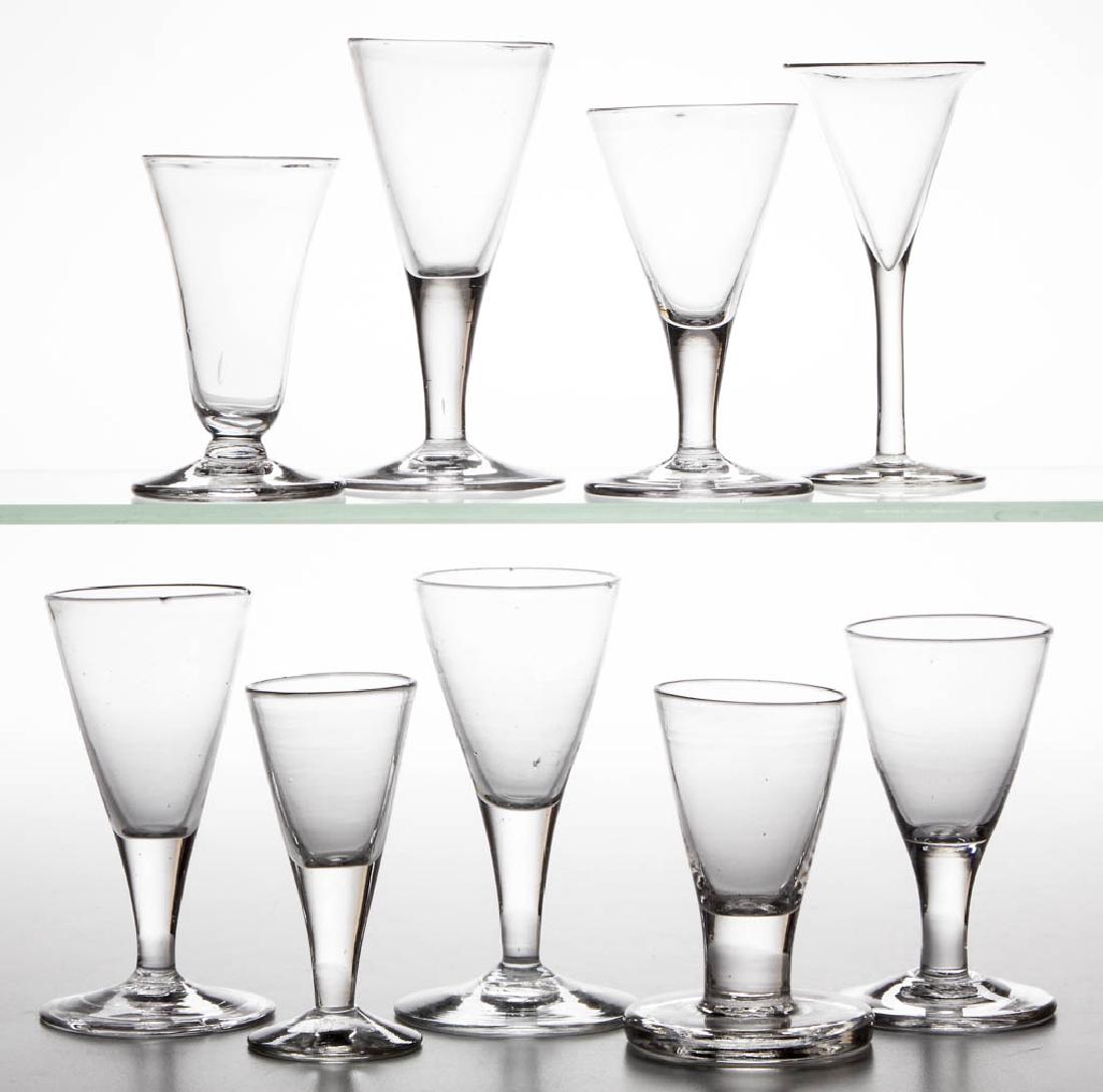 ASSORTED FREE-BLOWN DRINKING VESSELS, LOT OF NINE: ASSORTED FREE-BLOWN DRINKING VESSELS, LOT OF NINE, colorless lead and non-lead glass, comprising two firing glasses, one with thick foot, and seven wine glasses, most with rough pontil mark. 18th and 