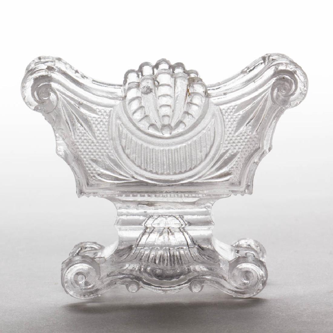 SL-18 SHELL PEDESTAL PRESSED OPEN SALT: SL-18 SHELL PEDESTAL PRESSED OPEN SALT, colorless, ornate shaped rim, acorn end panels, raised on a conforming pedestal with scrolling feet, rays to underside. Extremely rare. Possibly Boston & Sandwi
