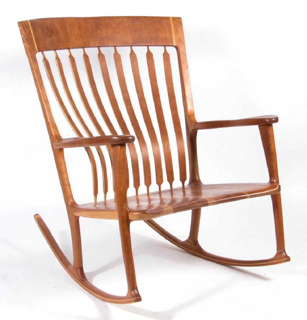 PARKER CONVERSE FIGURED CHERRY OVERSIZED "DIERDRA": PARKER CONVERSE FIGURED CHERRY OVERSIZED "DIERDRA" ROCKING CHAIR, finely crafted form of substantial proportions featuring nine floating bentwood slats, shaped arm rests, and generous plank seat, warm