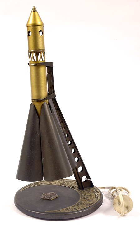 Misc, c1960, Rocket Lamp: Misc, c1960, Rocket Lamp (7x15") An unusual metal table lamp with a rocket model mounted on a round base designed so that when plugged in, the light in the base of the rocket makes the lam