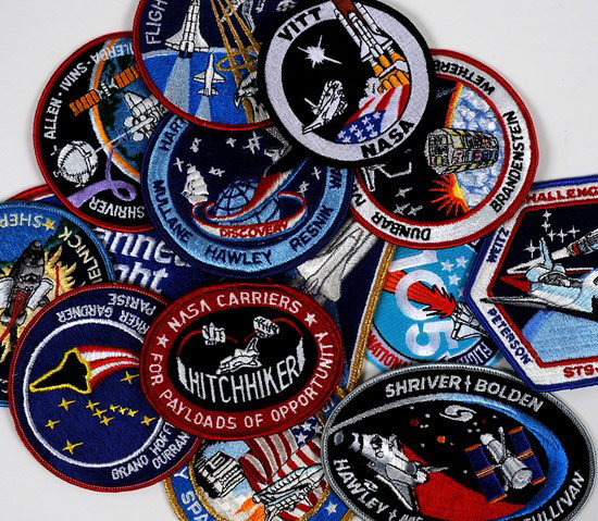 Shuttle Program, c1980s, Space Mission Patches: Shuttle Program, c1980s, Space Mission Patches. An interesting carton of embroidered patches, decals and lapel pins consigned by a long-time NASA employee. There are probably several hundred pieces in