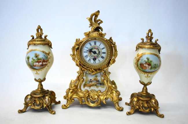 1880's Limoges 3 Piece Garniture Louis XVI Style: Central Clock with Porcelain Floral Painted Face above a porcelain painted panel with a scene of a country home, encased in an ormolu gilded foliate case. Interior stamped with CFH GDM France for Char