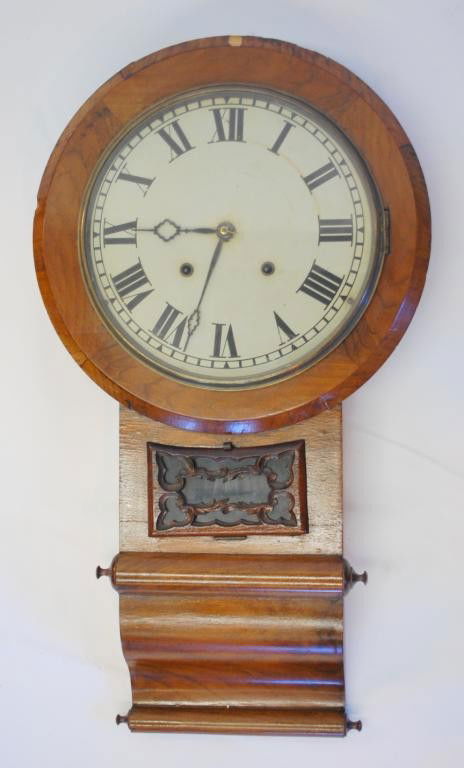 19th c. Schoolhouse Clock: Round top with long scrolled drop and carved door for viewing pendulum. Metal Painted Dial. 30" tall. 1.5" veneer chip loss at top of clock.