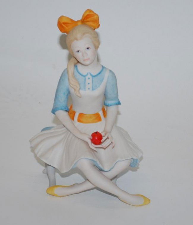 Cybis Porcelain figurine of a girl: dated 1971 Girl with bow in hair seated with apple. 7.5" tall.