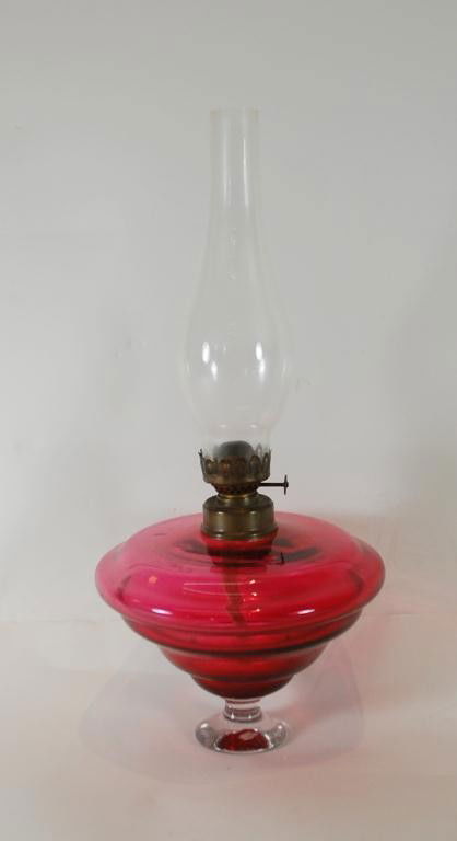 19th Century Cranberry Glass Oil Lamp: Small oil lamp with graduated levels throughout cranberry glass bulb with clear glass stem base. Blown glass, not molded. 15" tall
