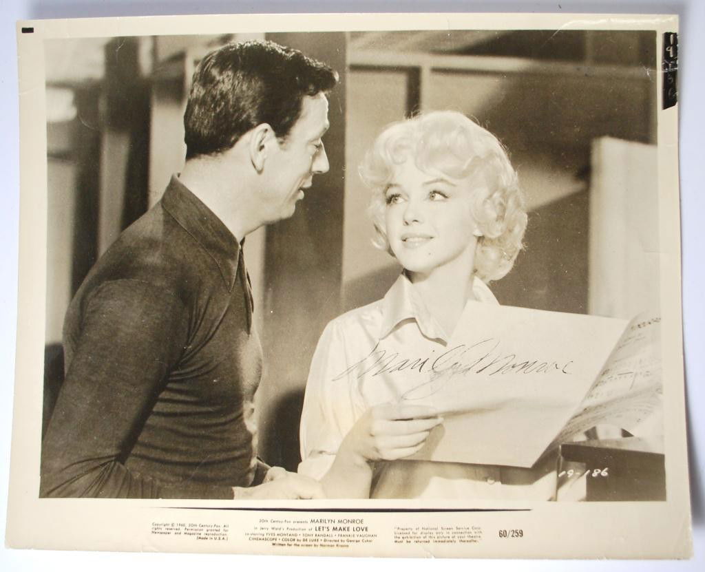 Marilyn Monroe Authographed Photo: book still of Marilyn Monroe and Yves Montand from movie Let's Make Love 1960, autographed lower right by Marilyn Monroe. 8 x 10"