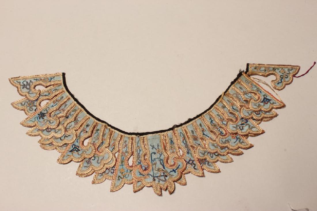Chinese Embroidered Qing Dynasty Collar,: of ruyi form, decorated with Buddhist precious items in tones of blue and accented n tones of blue and green accented in gilt, l 36cm