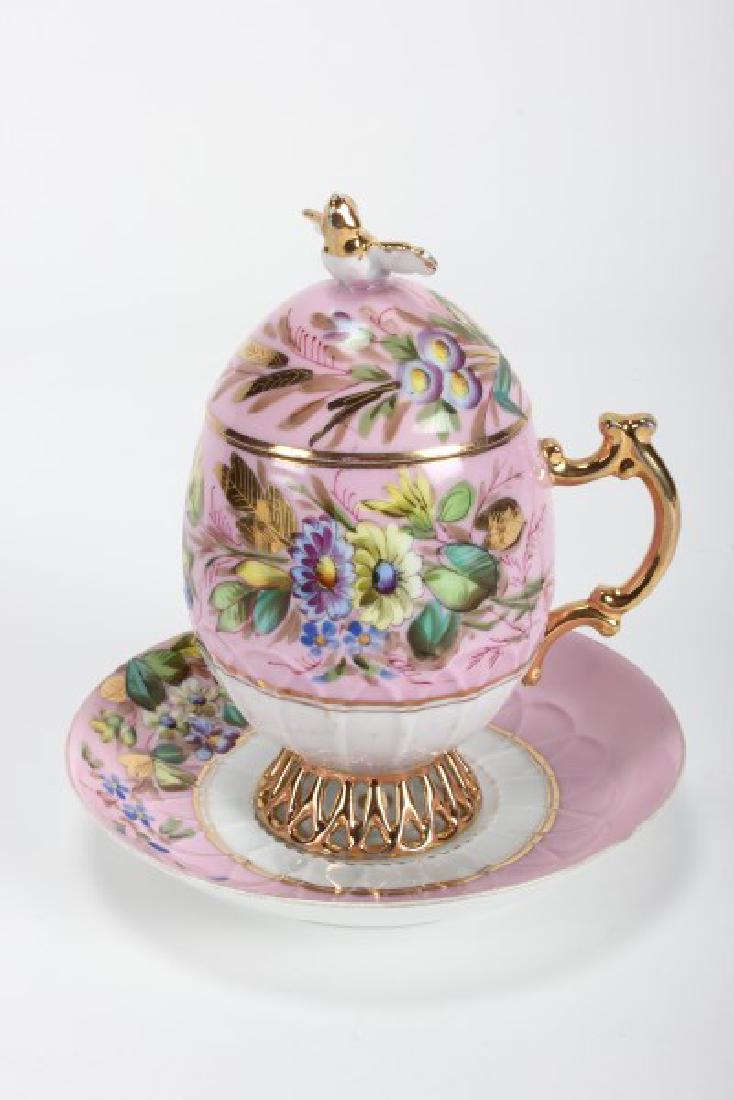 Russian Kuznetsov Porcelain Covered Easter Cup: and Saucer, the egg shaped cup and cover, and saucer with floral decoration gilt accented on a pink ground, stamped blue factory mark to base of cup and saucer, h 17.5cm