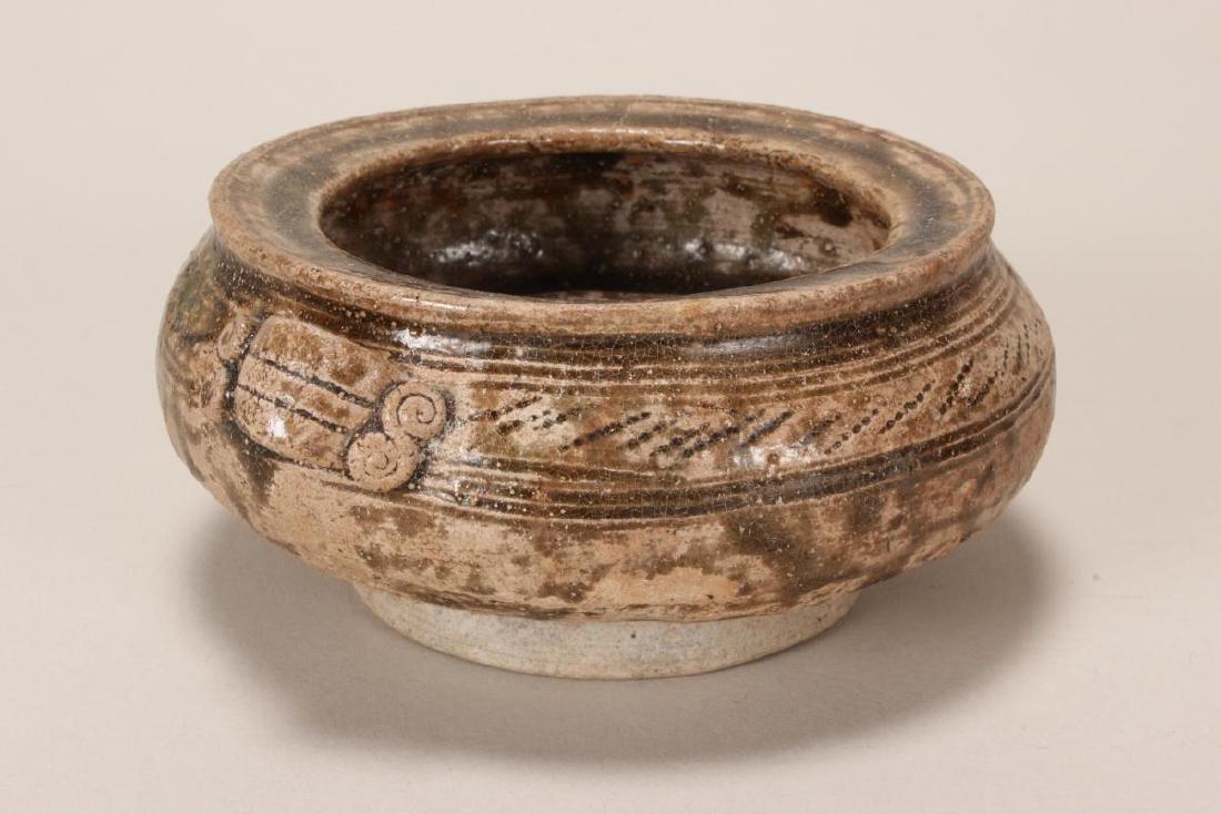 Chinese Early Western Zhou, 9th/10th Century Bowl,: of squat baluster form, set with lug handles, with borders of etched decoration, raised on a circular foot, d 9.7cm Reference: "Ther Ceramic Art of China", OCS, Victoria and Albert Museum, London, 197