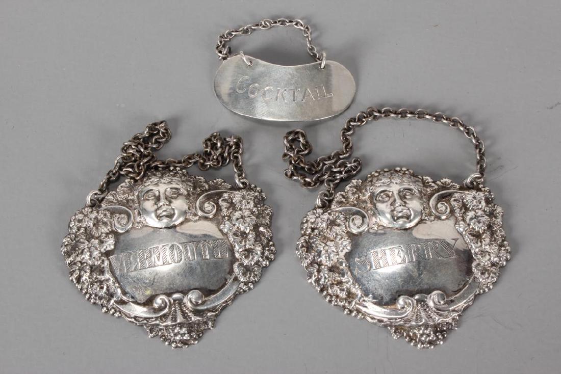 Pair of English Sterling Silver Decanter Labels,: of cartouche form, decorated with masks and grape vine decoration, together with another English sterling silver decanter label (3)