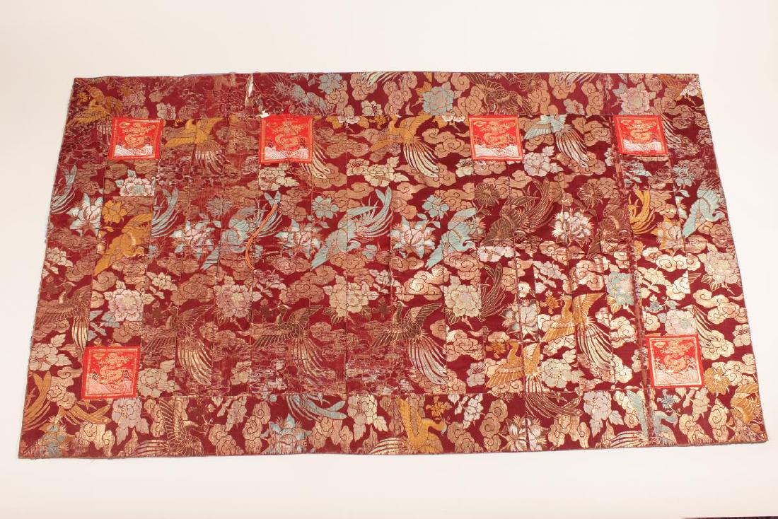 Chinese Buddhist Silk Cassock,: decorated with phoenix among flowers, in tones of turquoise, white and gilt on a maroon ground, accented with six red and gilt dragon badges, 202cm x 114cm