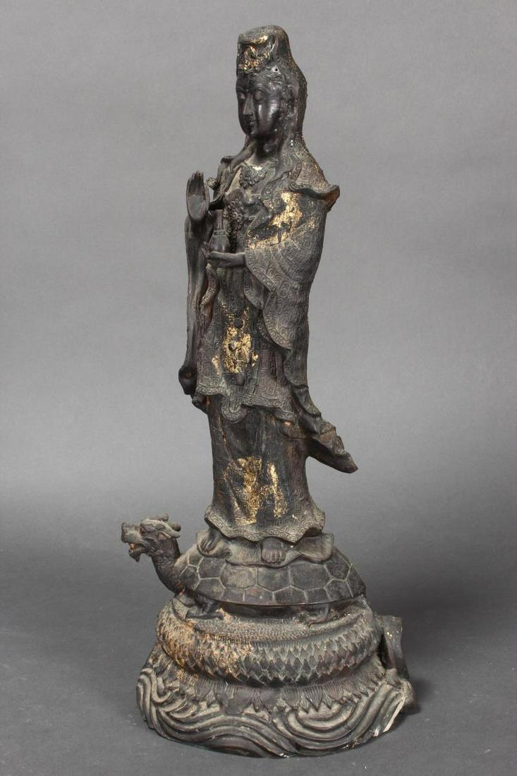 Chinese Figure of Kwan Yin,: depicted in elaborate robes standing on tortoise, with one hand raised, the whole resting on a lotus and wave base, accents of gilt, h 48.5cm
