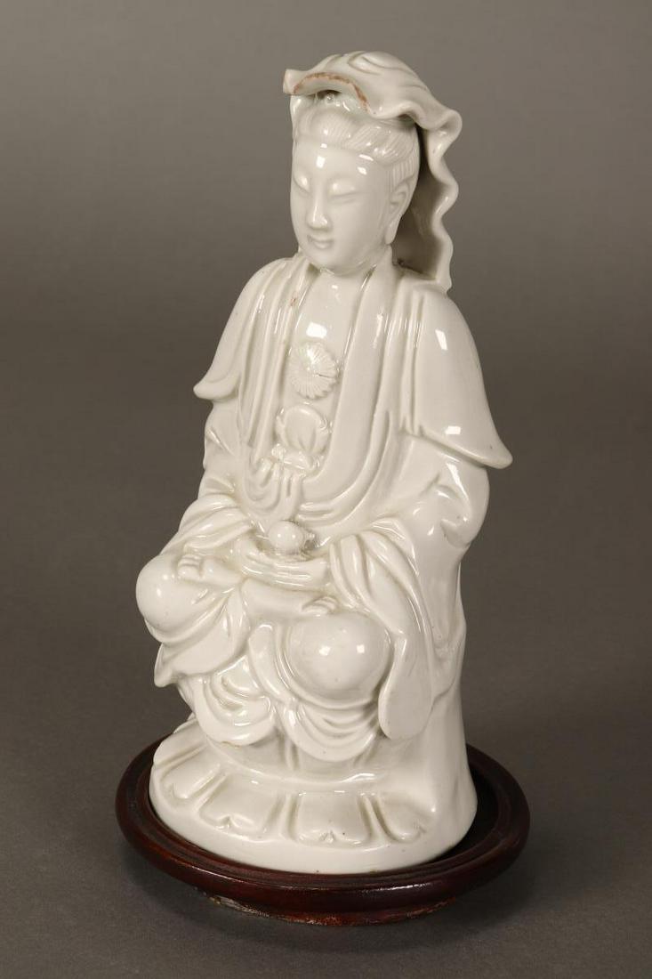 Chinese Dehua Porcelain Figure of Kwan Yin,: depicted seated wearing head dress, with hands resting in lap and legs crossed on lotus base, on a wooden stand, h 18cm Provenance: The Ivan Ban Collection
