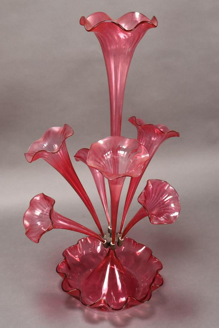Victorian Ruby Glass Centrepiece Epergne,: with large central flute, surrounded by six alternating flutes, the whole set within a ruby glass bowl with a pinched rim, height 65cm