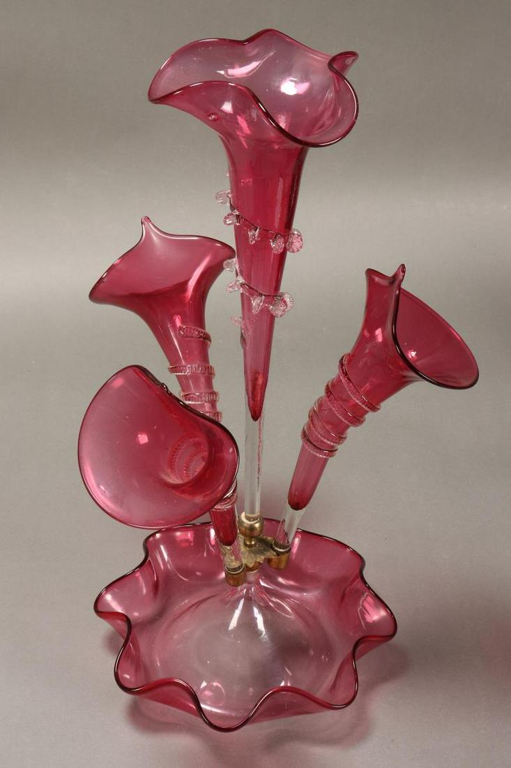 Late Victorian Ruby Glass Epergne,: with a central floriform trumpet vase, flanked by three trumpet vases, above a floriform bowl, height 51cm