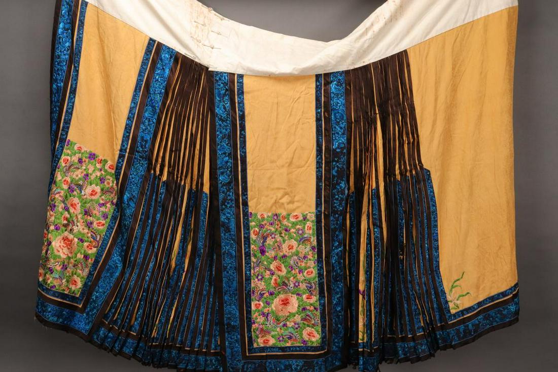 Chinese Late Qing Dynasty Silk Damask Skirt,: in pale yellow, with blue san lan trim, the skirt beautifully embroidered with panels of peonies butterflies and foliage, in tones of peach, green and purple, with orange damask lining, length 103cm