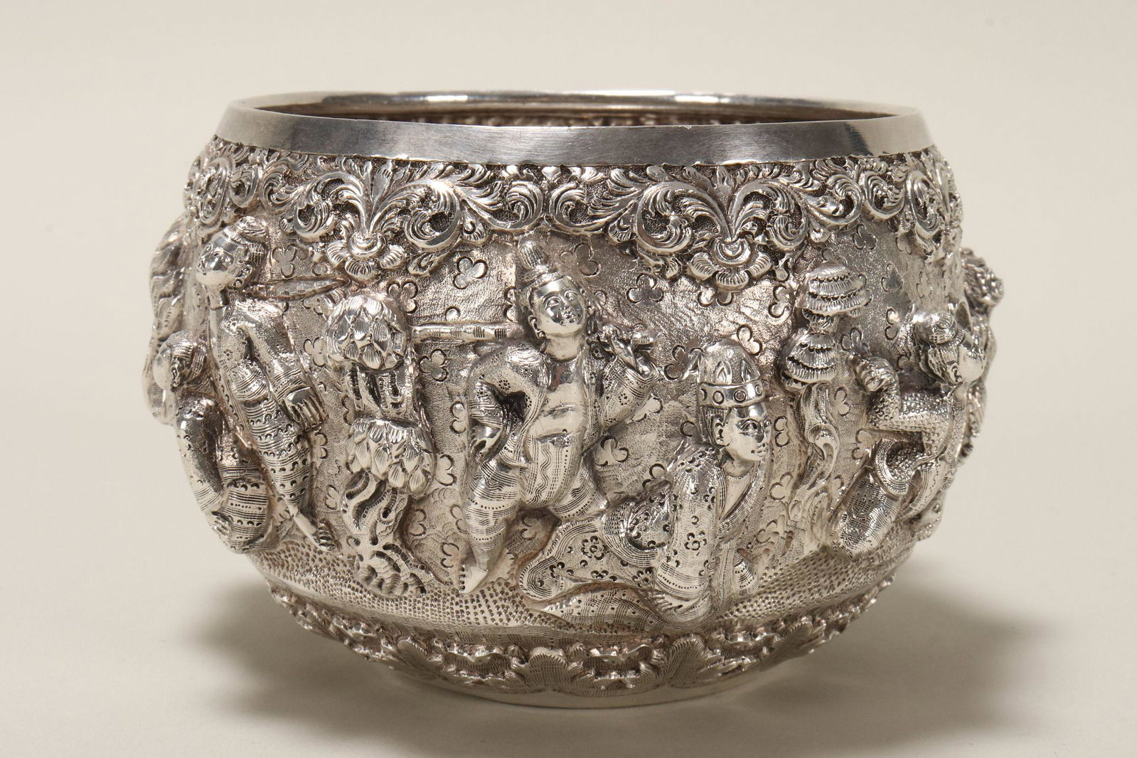 Burmese Silver Ceremonial Bowl,: decorated in repousse with figures and deities in mythical scenes, accented with floral and acanthus motifs, incised figure to base, total weight 287gm, height 9cm and diameter 13cm