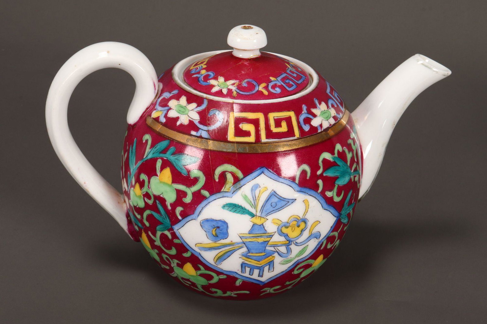 19th Century Russian Porcelain Tea Pot,: by the Gardner factory, made for the eastern market, of spherical form, decorated with cartouches of table vase and flowers, surrounded by scrolling foliage, in tones of green and yellow on a maroon/p