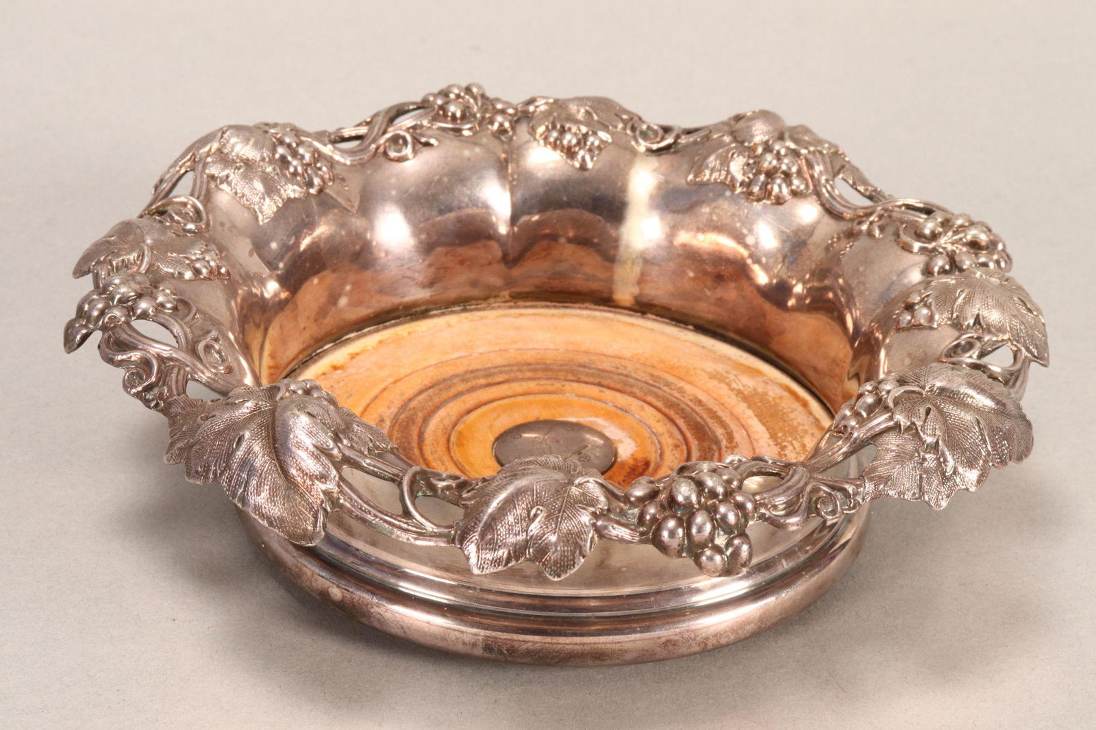 Mid 19th Century Sterling Silver Bottle Coaster: English, hallmarked with lion passant, city and year mark rubbed, D&S, in pierced leaf and grape design above a lobed shoulder, with circular turned timber base with centre roundel containing hallmark