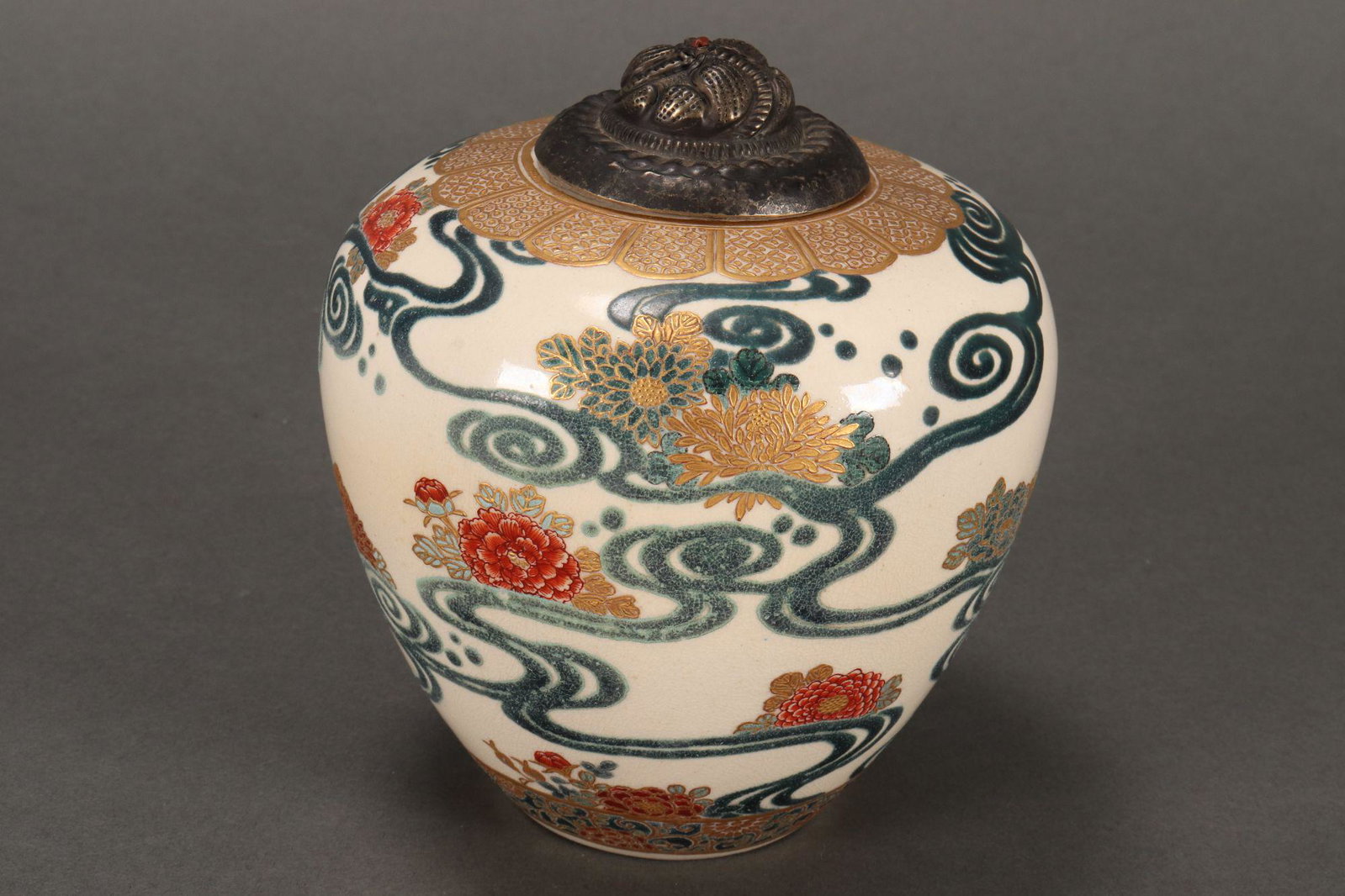 Japanese Meiji Period (1868-1912) Satsuma Vase,: of ovoid form, decorated with peonies amongst stylised scroll, with gilt and brocade accents, with embossed silver lid, signature and marks to base, height 13cm