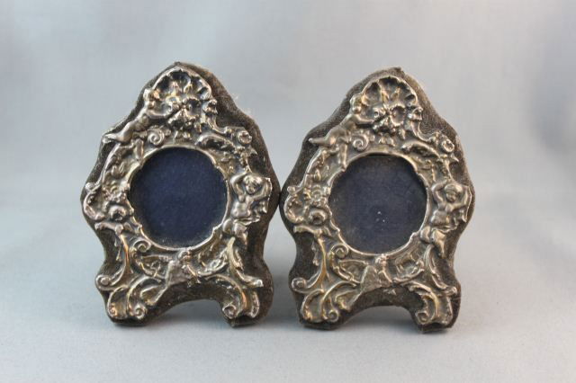 Pair of Edwardian Sterling Silver Photo Frames,: of shaped form, embossed with putto, shells and birds, (2)