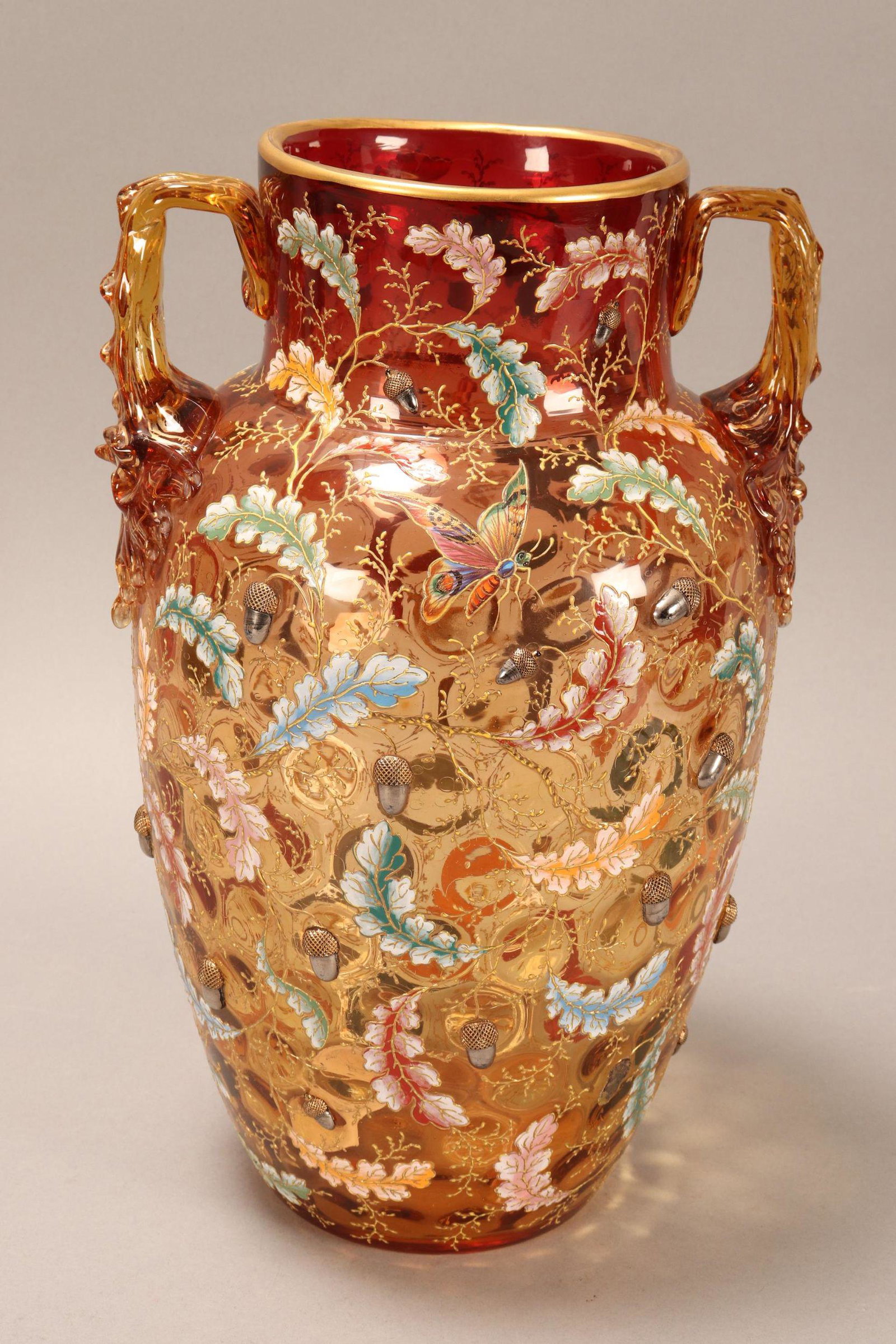Handsome 19th Century Moser Glass Vase,: of baluster form with a cylindrical neck flanked by twin handles, in Amberina glass, decorated with enamelled butterfly and insect surrounded by enamelled oak leaves and applied acorns, with gilt acce