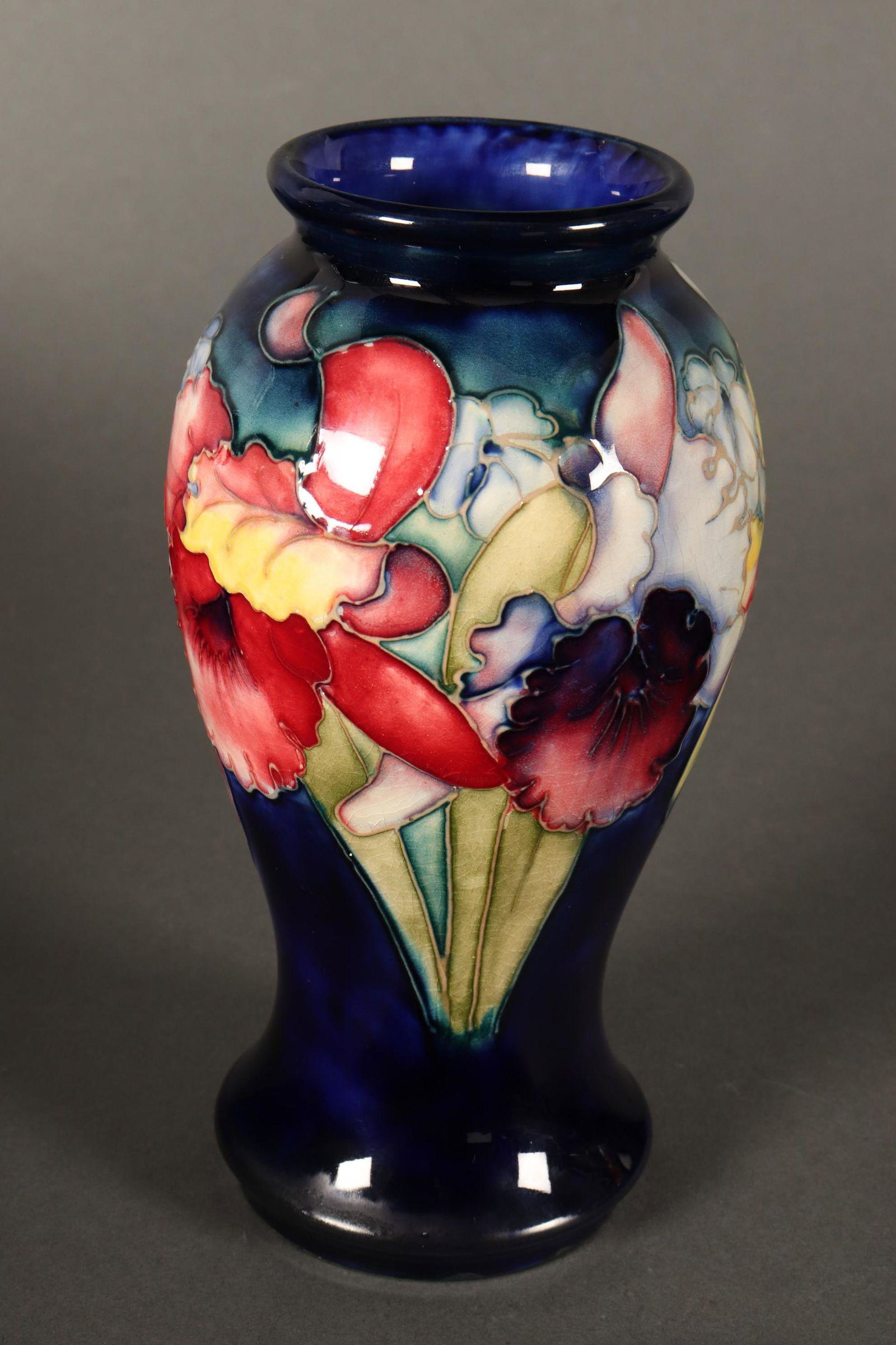William Moorcroft 'Orchid' Vase,: c.1928-1949, of baluster form with a short flaring rim and wide foot, decorated with orchids on a rich royal blue ground, with impressed signature, 'Potter to H.M The Queen' and 'Made in England' mark