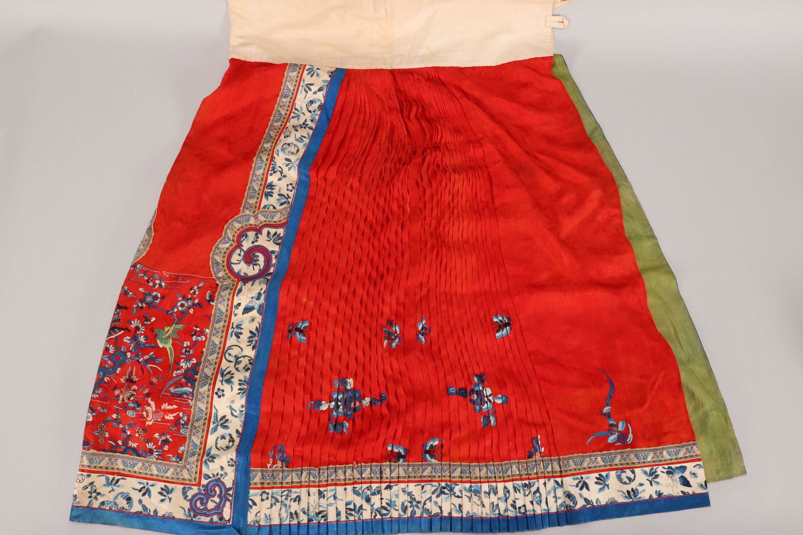 Chinese Embroidered Concertina Skirt,: embroidered with panel depicting green bird and two fish, surrounded by flowers, in tones of blue, white, pink and brown, accented with embroidered white border, with white cotton waistband and green 
